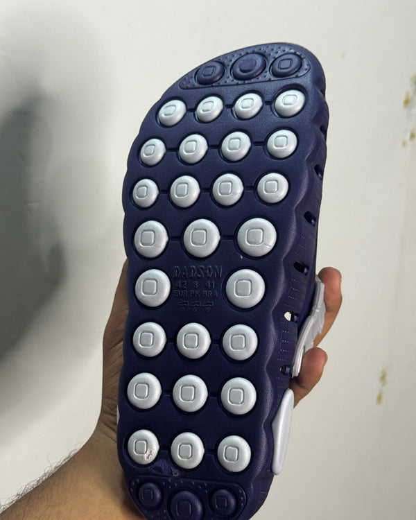 Textured grip outsole of a navy-blue and white clog-style slipper